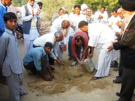 Villagers and volunteers planting trees together in an adopted village