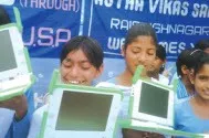 Students holding green XO laptops at a village school